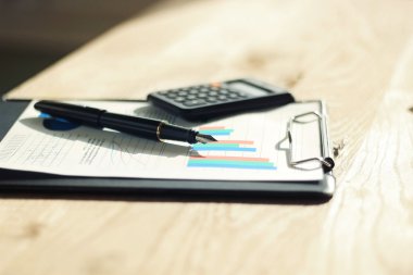 kalem, hesap makinesi ve mali grafik üzerinde bir çalışma alanı 