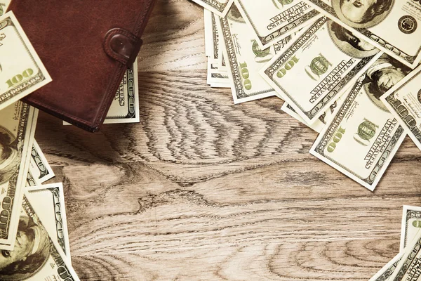 Foto peněženku a bankovek dolarů na dřevěné pozadí — Stock fotografie