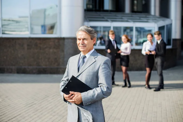 En framgångsrik affärsman med dokument på bakgrund av kontoret — Stockfoto