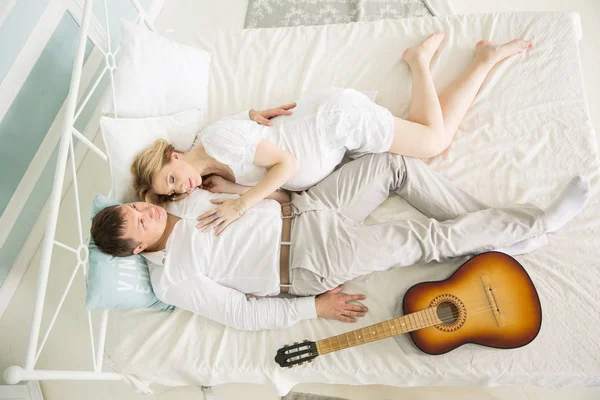 Marito amorevole con una chitarra e sua moglie incinta sul letto — Foto Stock