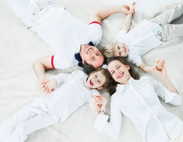 Spaß freundliche Familie auf dem Teppich liegend, Händchen haltend. — Stockfoto