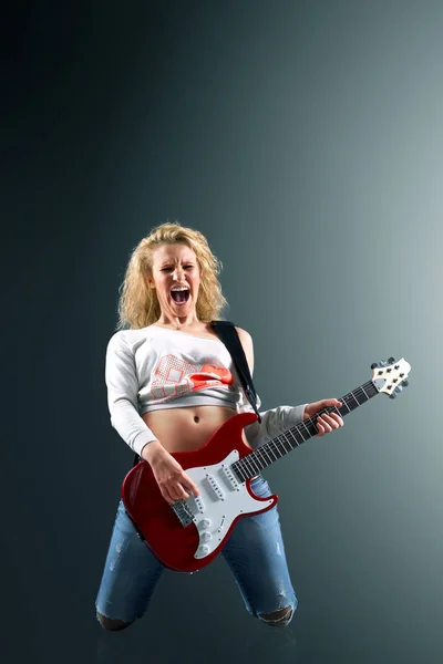ギターを持つ美しい若いブロンドの女性はロックソングを歌います — ストック写真