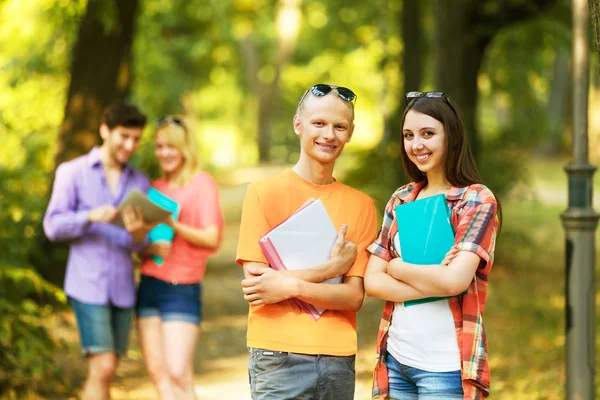 Skupina happy studentů s knihami v parku za slunečného dne. — Stock fotografie