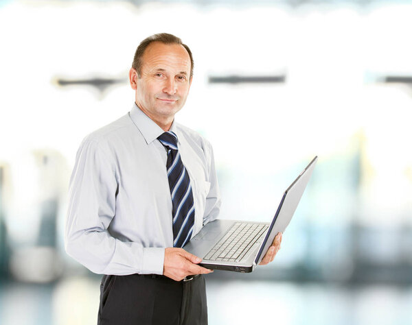 бизнесмен - профессионал с открытым ноутбуком на заднем плане
