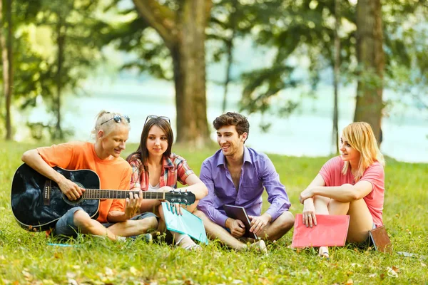 En grupp studenter med en gitarr som vilar i parken — Stockfoto