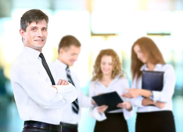 Erfolgreicher Geschäftsmann steht mit seinen Mitarbeitern im Hintergrund im Büro — Stockfoto