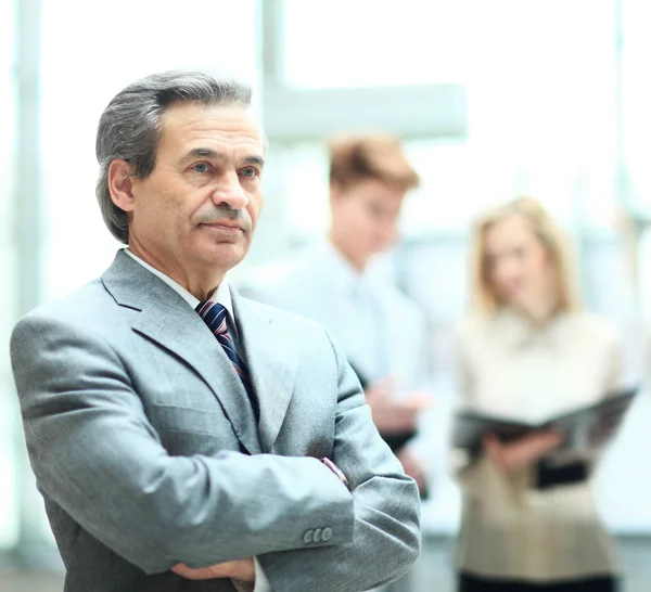 Glad smart affärsman med lagkamrater som diskuterar i bakgrunden på kontoret — Stockfoto