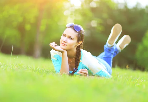 Mladá hezká žena ležící na trávě při západu slunce — Stock fotografie