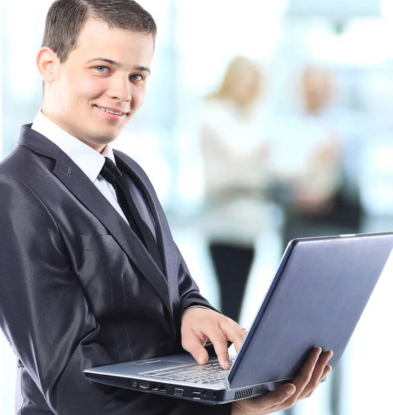 Glücklicher smarter Geschäftsmann mit Laptop in der Hand im Hintergrund des Teams — Stockfoto