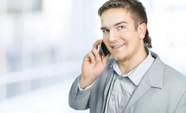 Homem de negócios de sucesso a falar ao telefone. foto um escritório brilhante . — Fotografia de Stock