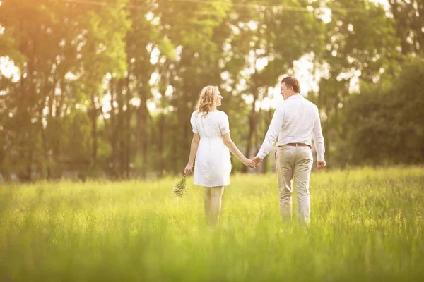 Lyckligt par - gravid kvinna och hennes make gå på picknick i gräset. — Stockfoto