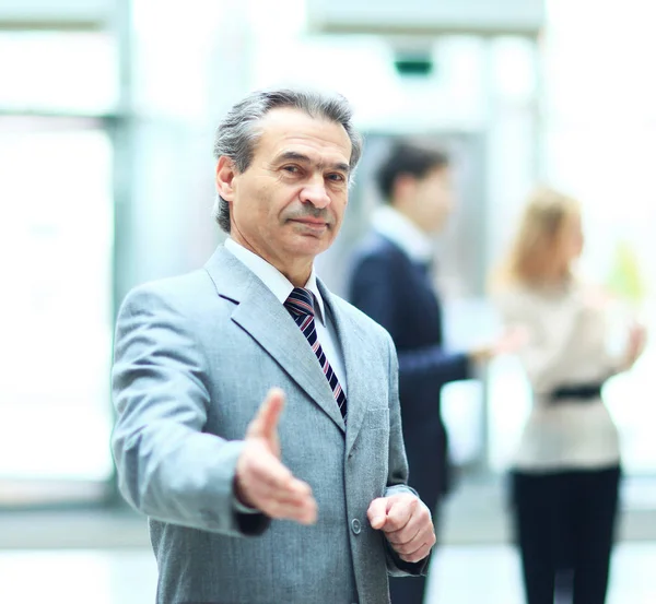 Welcoming business man ready to handshake with hand extended,   co-operate against the background of the work  his team — Stock Photo, Image