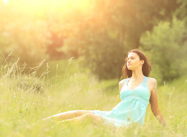 Красивая молодая женщина наслаждается солнцем на летнем поле
