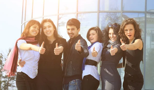 Grupo de estudiantes universitarios sonriendo amistosos de pie uno al lado del otro con los brazos extendidos hacia adelante y los pulgares hacia arriba —  Fotos de Stock