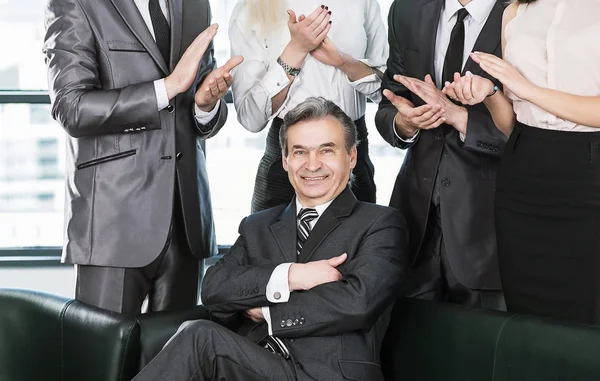 Experienced businessman at the age of applause in the background of their employees — Stock Photo, Image