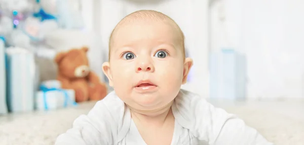 Verbaasd schattig klein kind op kerstavond thuis op het tapijt — Stockfoto