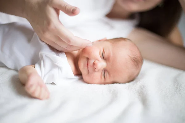 Moeder strelen van een pasgeboren baby liggend op het bed — Stockfoto