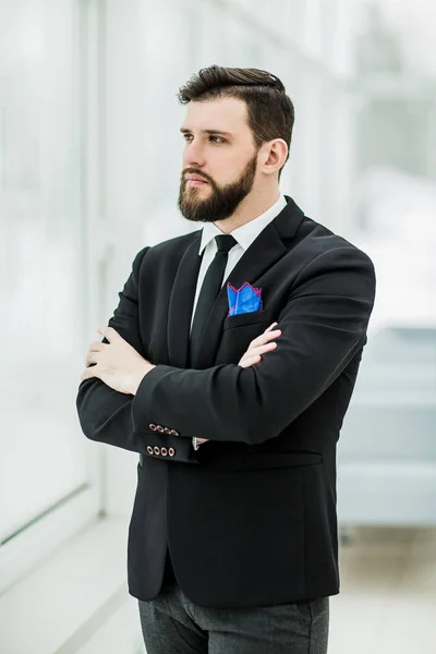 Erfolgreicher Geschäftsmann steht in hellem Büro am Fenster. — Stockfoto