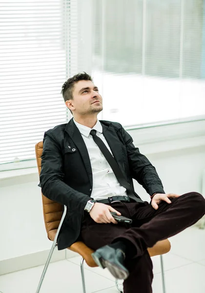 Retrato de exitoso hombre de negocios con teléfono inteligente sentado en una oficina moderna — Foto de Stock