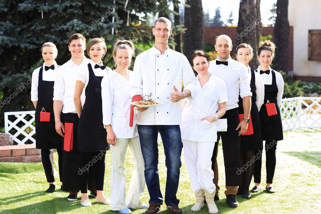 group of waiters in the branded clothes are on the lawn