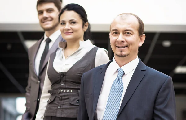 Glimlachende medewerkers die rond hun manager staan — Stockfoto