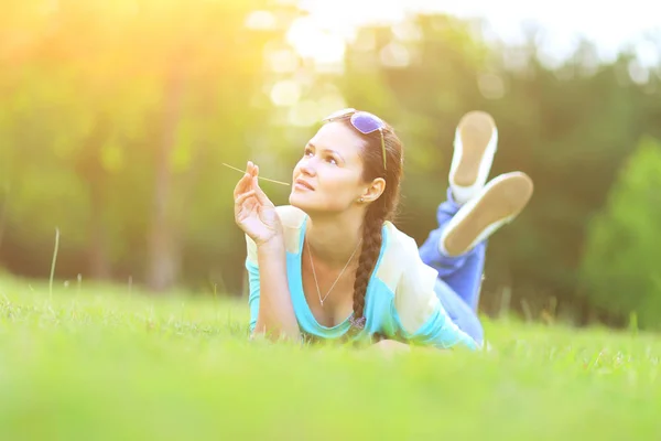 Mladá krásná žena ležící na trávě na letní západ slunce. Přirozené štěstí, zábava a harmonie. — Stock fotografie