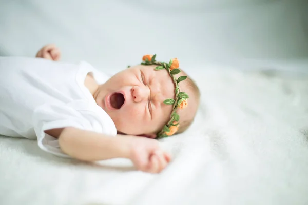 Pasgeboren baby in de kranslegging op het bed en gegaap — Stockfoto