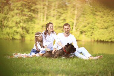 Güneşli bir yaz gününde piknikte köpekli mutlu bir aile. pregn