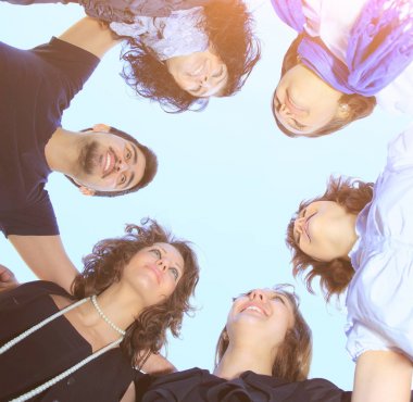bir grup genç insan birbirine bakarak gökyüzü üzerinde bir daire içinde