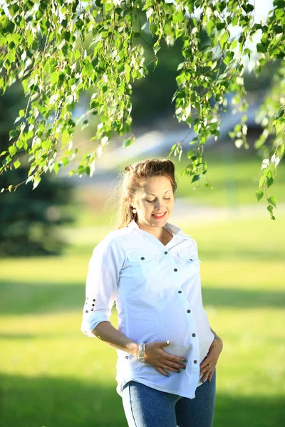 Giovane donna incinta in una passeggiata nel parco in una giornata di sole — Foto Stock