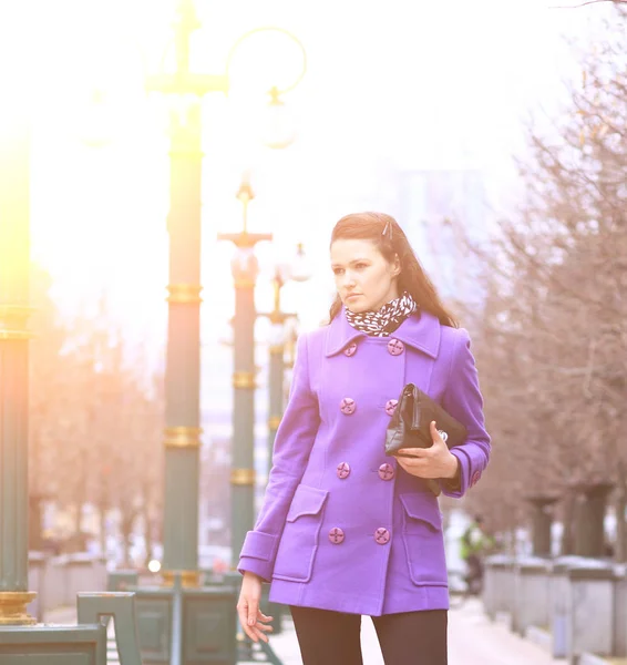 穿紫色上衣的手提包站在公园的道路上的漂亮女孩 — 图库照片