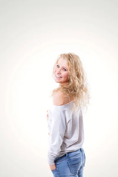 Belle jeune femme blonde en gilet et jeans sur fond blanc — Photo