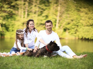 Güneşli bir yaz gününde piknikte köpekli mutlu bir aile. pregn