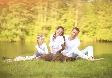 Güneşli bir yaz gününde piknikte köpekli mutlu bir aile. pregn