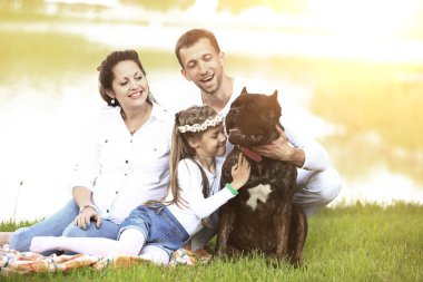 Güneşli bir yaz gününde piknikte köpekli mutlu bir aile. pregn
