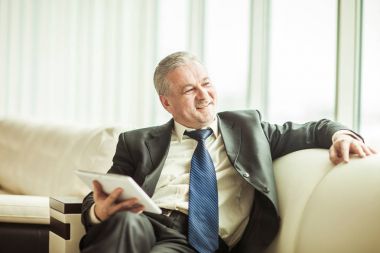 özel ofis kanepede oturan dijital tablet ile başarılı iş adamı