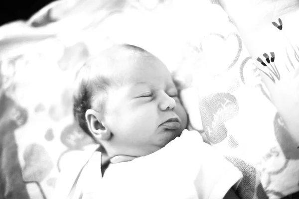 Black - and-white photo: a newborn baby sleeping in the crib on — Stock Photo, Image