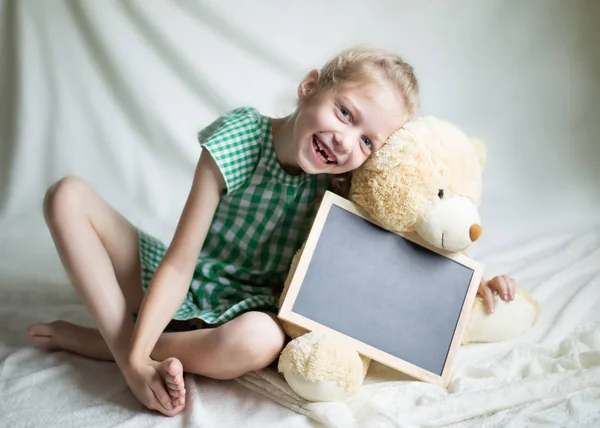 Niña sosteniendo un juguete suave con palabras de felicitación para el —  Fotos de Stock