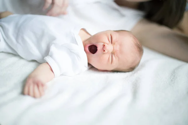 Pasgeboren baby liggend op het bed en gegaap — Stockfoto
