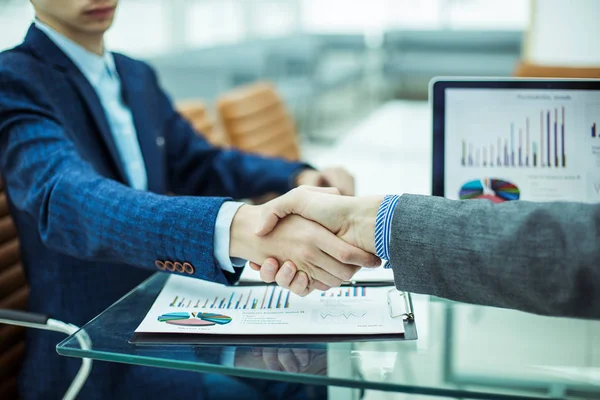 Handshake financial partners on the background of the workplace with financial papers — Stock Photo, Image