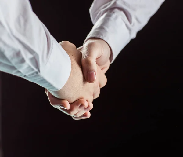 Konzept einer verlässlichen Partnerschaft: Handschlag von Geschäftspartnern aus nächster Nähe auf schwarzem Hintergrund. — Stockfoto