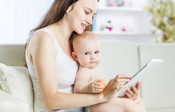 Onnellinen äiti osoittaa hänen vuotiaan vauvan kuvia digitaalinen tabletti — kuvapankkivalokuva