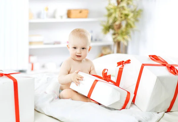 Bebé lindo de un año jugando con las compras en cajas en el sofá —  Fotos de Stock