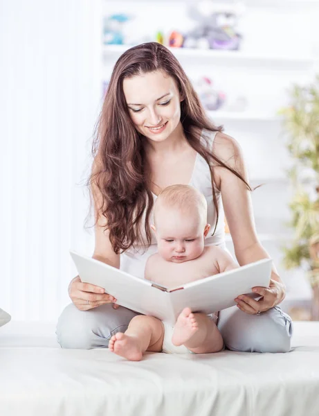 Madre feliz leyendo un libro a su hijo de un año — Foto de Stock