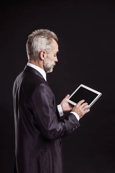 Erfaren affärsman med digital tablett på svart bakgrund. — Stockfoto