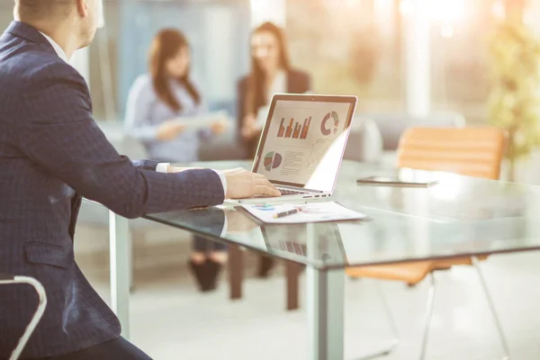 Hombre de negocios exitoso que trabaja en el ordenador portátil con datos financieros en el lugar de trabajo en una oficina moderna. — Foto de Stock