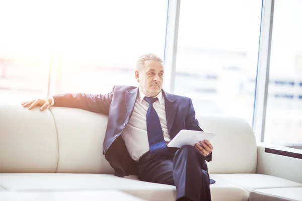 Exitoso hombre de negocios con tableta digital sentado en el sofá en la oficina . — Foto de Stock