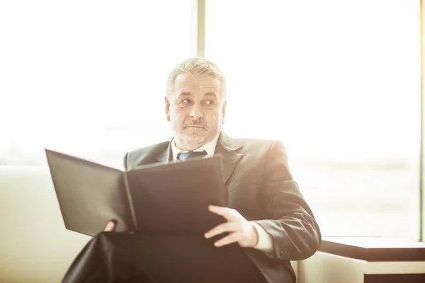 Erfolgreicher Geschäftsmann studiert Arbeitspapiere auf dem Sofa im Privatbüro — Stockfoto