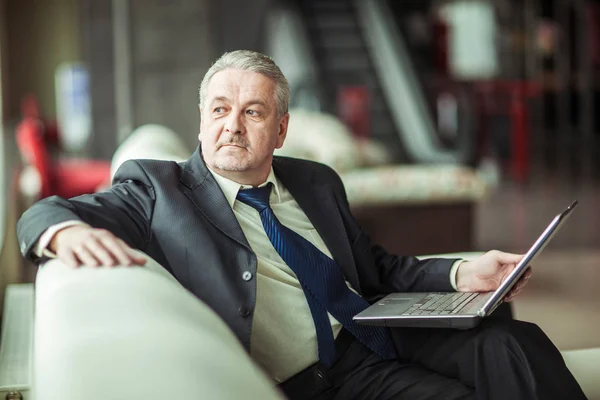 Experienced businessman working on laptop sitting on sofa in a private office — Stock Photo, Image