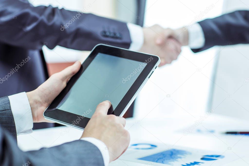 businessman with digital tablet on background of business partners handshaking